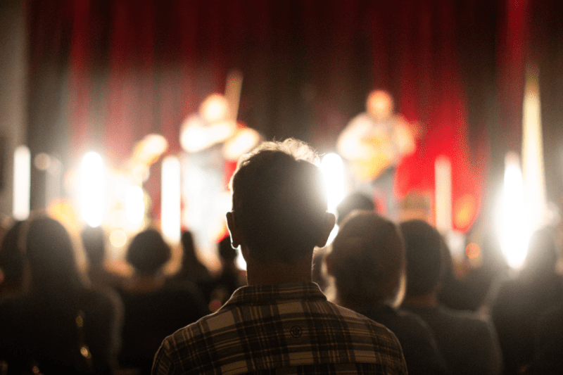 Audience members watch a performance with atmospheric lighting